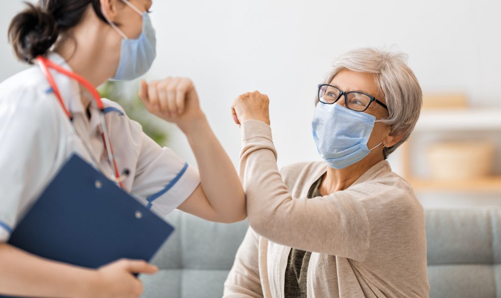 Patient and staff with masks on touching elbows